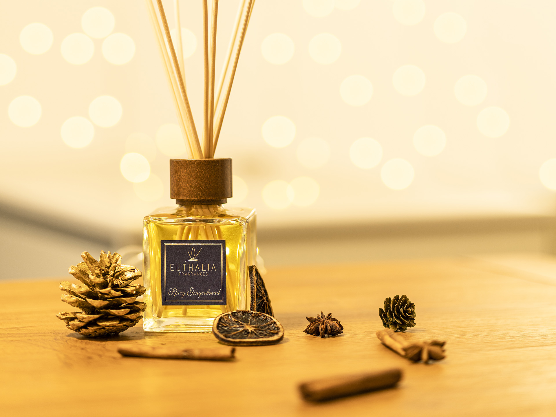 Profumo ambiente natalizio Euthalia Fragrances Spicy Gingerbread con diffusore e decorazioni festive su sfondo luminoso. Christamas perfume. Profumo di Natale